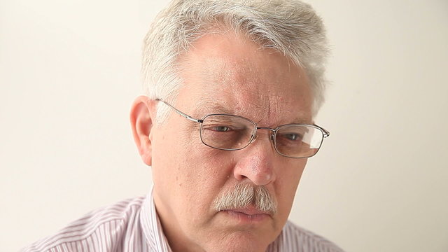 senior man with glasses experiencing fatigue and blurry vision