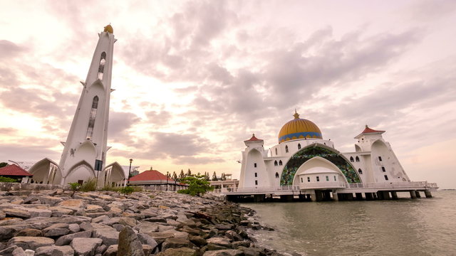timelapse 4k footage of a beautiful sunrise at Melaka Strait Mosque with moving and changing color clouds. Panning.