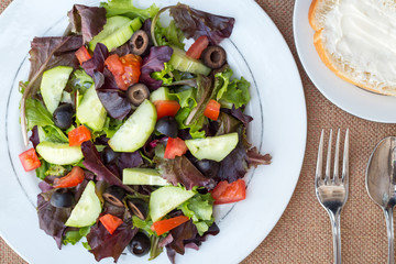 Chicken salad with avocado, mixed greens, cucumbers, tomatoes, and olives.