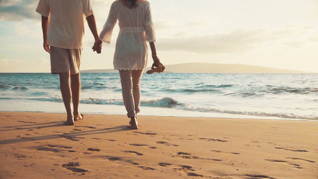 Sunset Walk on a Tropical Beach. Older Couple Holds Hands and Walks Down the Beach at Sunset Getting Their Feet Wet