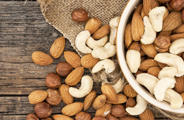 Almonds, cashew and hazelnuts in ceramic bowl on a rustic wooden