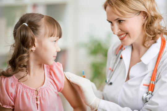 Positive pediatrician doctor vaccinating or inoculating preschool child