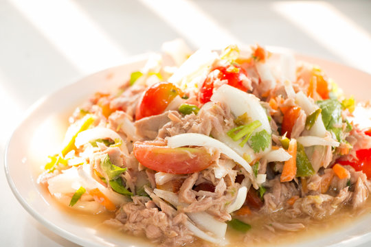 Spicy Tuna Salad onion and tomatoes in plate put on wooden background , Thailand cuisine.