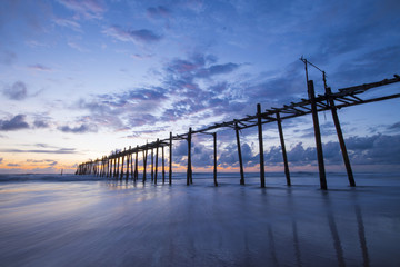 Fototapeta premium old wooden bridge in Natai beach with beautiful sky at twilight