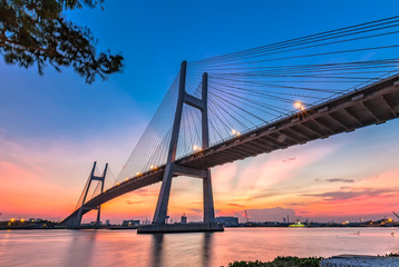 Obraz premium Ho Chi Minh City, Vietnam - August 11th, 2014: architectural beauty bridge steel wire shining moments before sunset rays shooting up from horizon, lights like stars beautiful in Ho Chi Minh, Vietnam