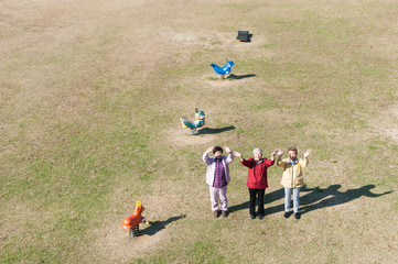 公園に立って手を振る3人の日本人高齢者