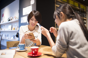 Women who are looking at the mobile phone in a cafe