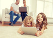 smiling sister with tablet pc and parents on back