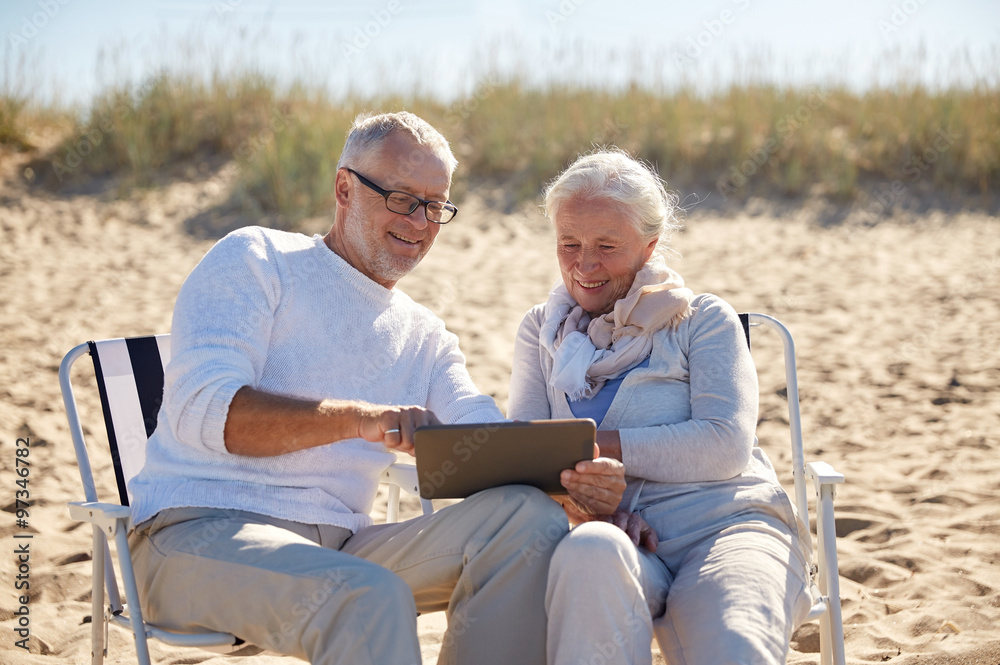 Wall mural happy senior couple with tablet pc on summer beach