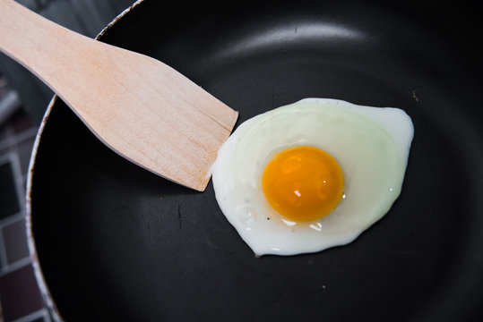 Fried egg and wooden flipper on frying pan