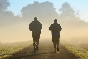 Two men running in the morning fog.