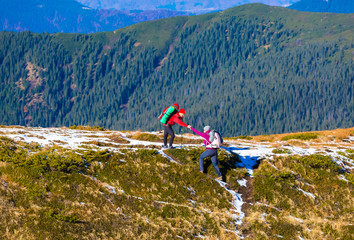 Man helping Woman to climb on steep Mountain Ridge