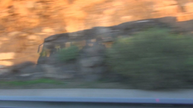 Shadow cast by traveling bus on rocks filmed through the bus's window. Blur speed background