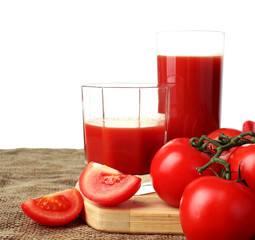 Tomato juice pour into glasses and ripe tomatoes on a white background..