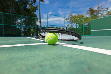 Tennis ball and racquet on court
