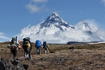 Poster Hiking on Kamchatka: travelers go to mountains on background of volcanoes © Alexander Piragis