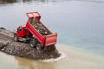 Red dump truck unloading earth fill © PiLensPhoto