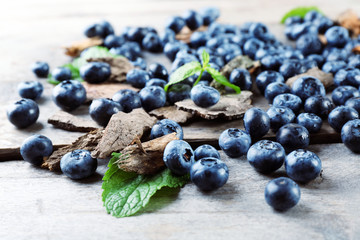 Tasty ripe blueberries with green leaves on wooden table close up