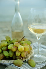 Romantic composition of white wine and grape on sandy beach