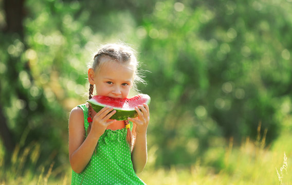 Small girl eating watermelons on lawn