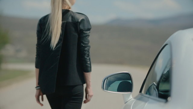 Successful woman standing next to the sports car