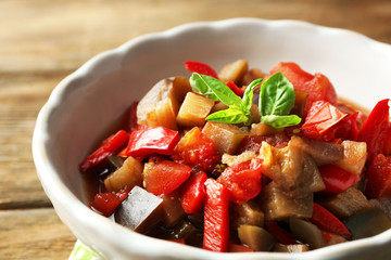 Ratatouille in bowl, on wooden table background
