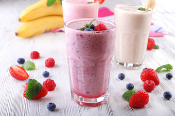 Milkshakes with berries on light wooden background