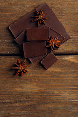 Black chocolate pieces with spices on wooden background