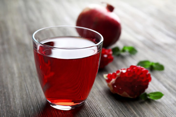 A glass of tasty juice and garnet fruit, on wooden background