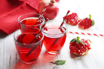 Three glasses of tasty juice and garnet fruit, on wooden background