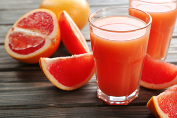 Glass of grapefruit juice and fresh fruits on wooden background