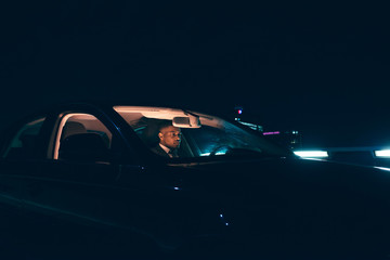 Man driving car in city at night.