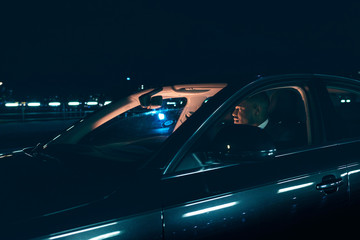 Fototapeta na wymiar Hispanic man in car at night with city lights.