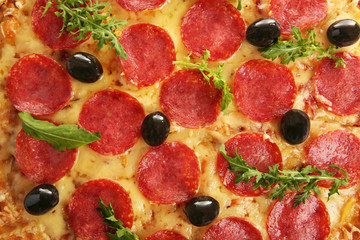 Pepperoni pizza with olives and arugula, close-up