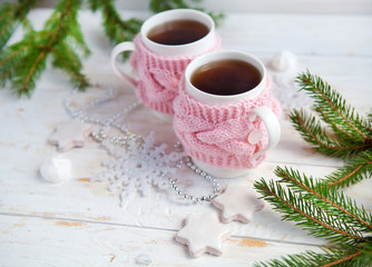 Christmas tree, cookies and cup of hot tea in knitted cup holder  on white wooden table