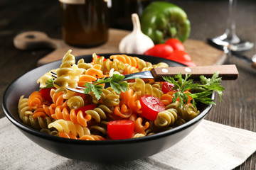 Delicious macaroni dish in black bowl on served wooden table