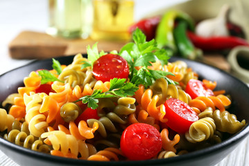 Delicious macaroni dish in black bowl on served grey wooden table