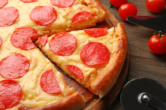 Hot tasty pizza with salami on wooden background, close up