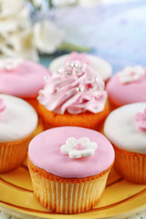 Tasty cupcakes on plate, on color wooden background