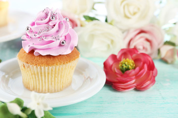 Tasty cupcake on plate, on bright background