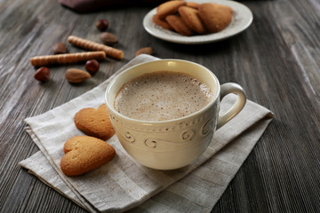 Cup of hot cacao on cotton serviette with cinnamon, almonds and heart shaped cookies