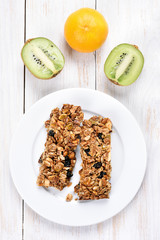 Cereal bars on white plate and fruits