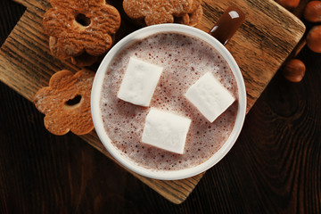 Cup of hot cacao with cookies and nuts on wooden kitchen board, close up