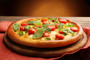 Pizza Margherita with arugula and napkin on  brown background