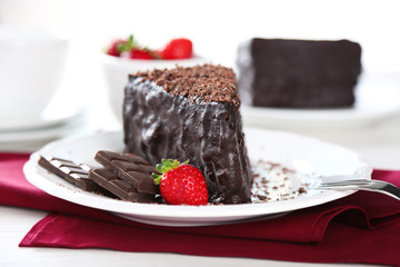 Chocolate cake with chocolate cream and fresh strawberries on plate, on light background