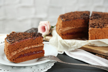 Sliced chocolate cake on plate, on wooden table  background