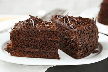 Sliced chocolate cake on wooden table, on light background