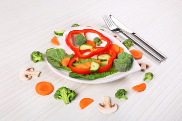 Useful cut vegetables on a plate in the form of heart on wooden table top view