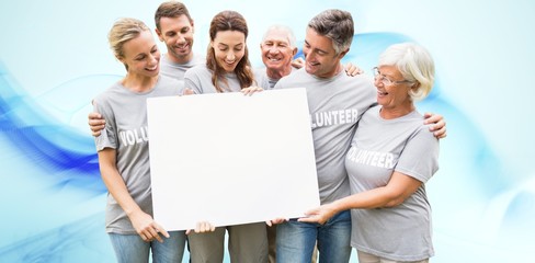 Composite image of happy volunteer family holding a blank  - Powered by Adobe