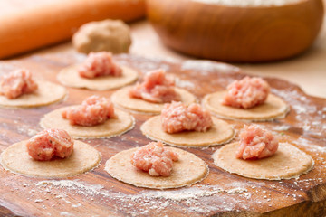 Dough circle from wholegrain flour filled with meat ready to pre